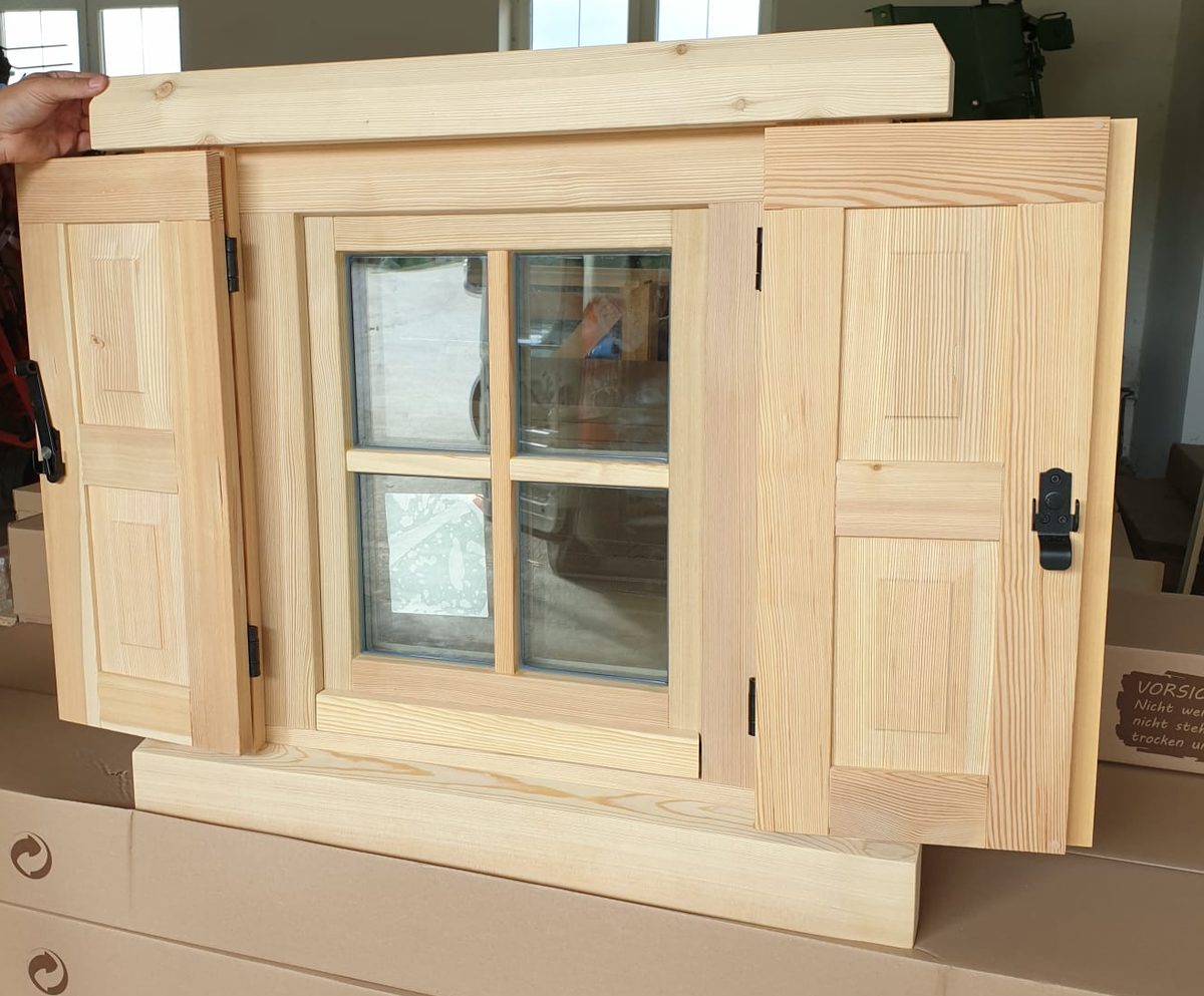 Kleines Holzfenster mit Sprossen und hölzernen Fensterläden