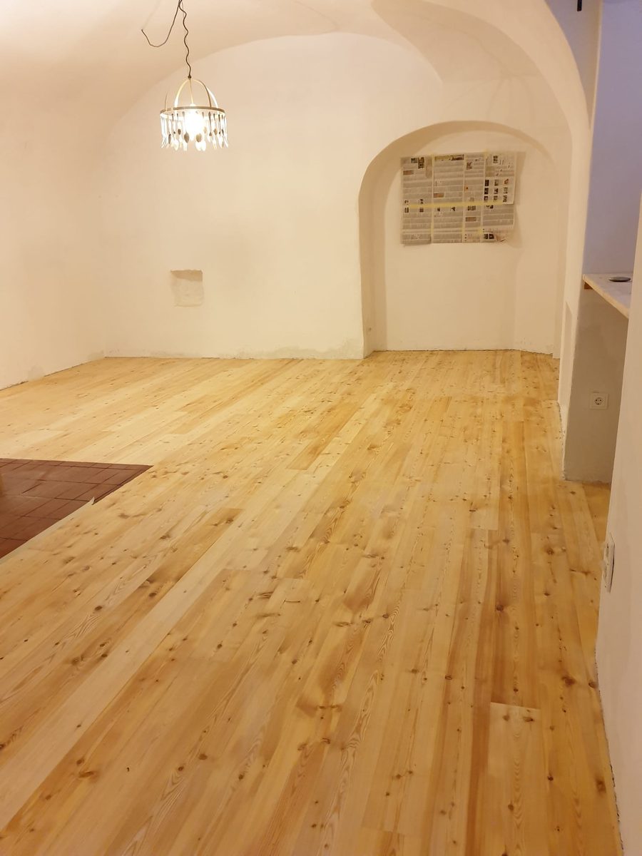 Frisch geschliffener, heller Holzboden in einem Gewölberaum